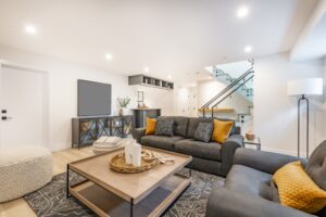 recreation party room with bar stairs with glass rails downstairs basement interior room with movie screen large grey sofa bohemian style