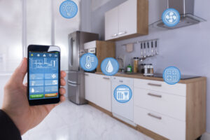 Close-up Of A Person's Hand Using Smart Home Application On Smartphone In Kitchen
