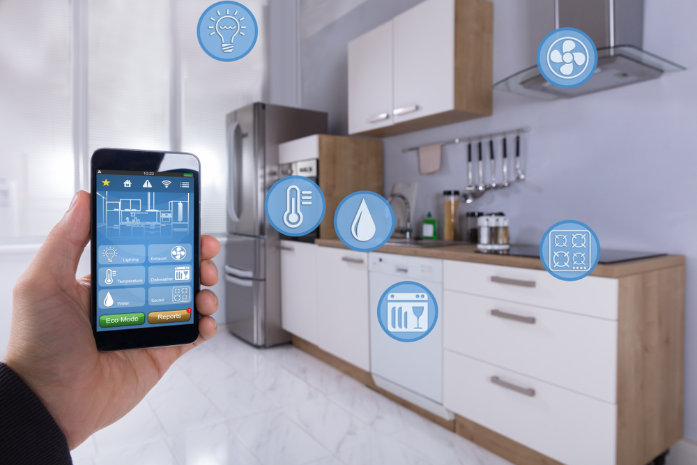 Close-up Of A Person's Hand Using Smart Home Application On Smartphone In Kitchen